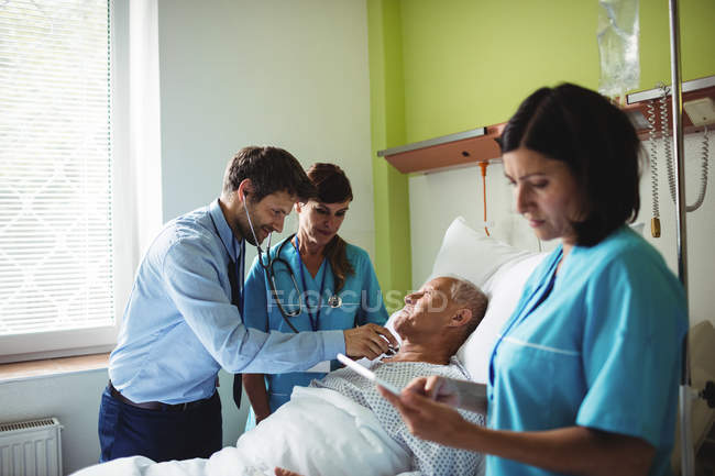 Мужчина-врач осматривает пожилого пациента в больнице — стоковое фото