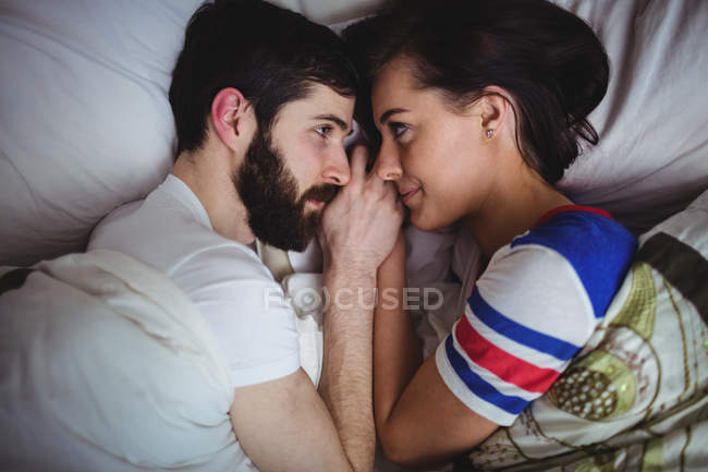 Paar schaut sich an, während es im Schlafzimmer auf dem Bett liegt — Stockfoto