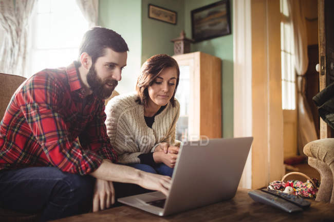 Jeune couple utilisant un ordinateur portable dans le salon à la maison — Photo de stock