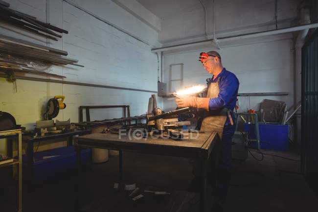 Male welder holding welding torch in workshop — Stock Photo