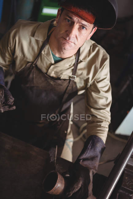 Retrato de soldador de pie cerca de la herramienta de trabajo en el taller - foto de stock