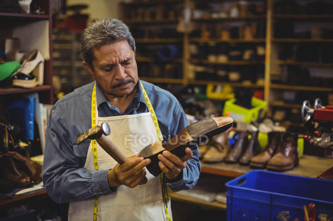 Обувщик стучит по обуви в мастерской — стоковое фото