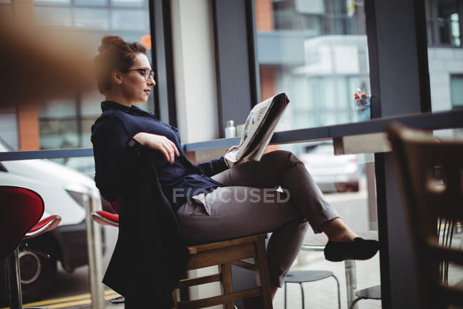 Full length of businesswoman reading newspaper in cafe — Stock Photo