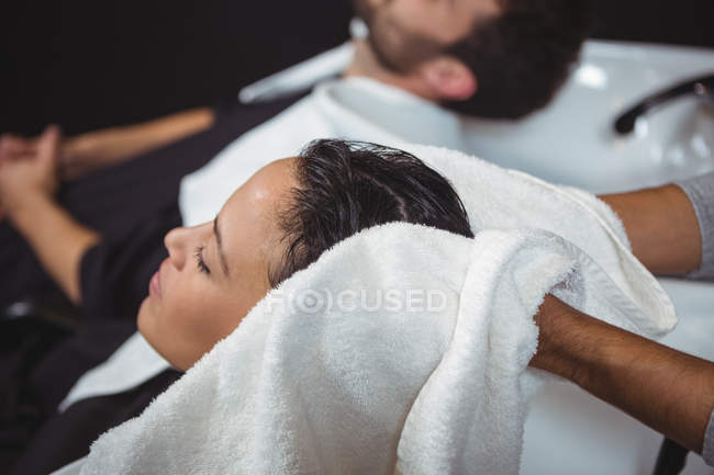 Peluquero mujer secadora pelo con toalla en el salón - foto de stock