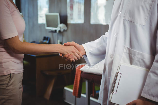 Immagine ritagliata del fisioterapista che stringe la mano alla paziente in clinica — Foto stock