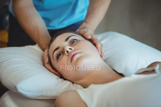 Fisioterapista maschile che fa massaggi alla testa a pazienti di sesso femminile in clinica — Foto stock