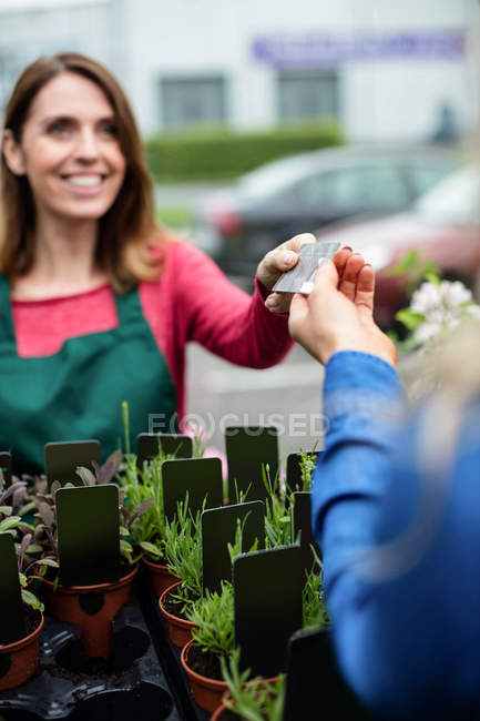 Mulher fazendo pagamento com cartão de crédito para florista no centro de jardim — Fotografia de Stock