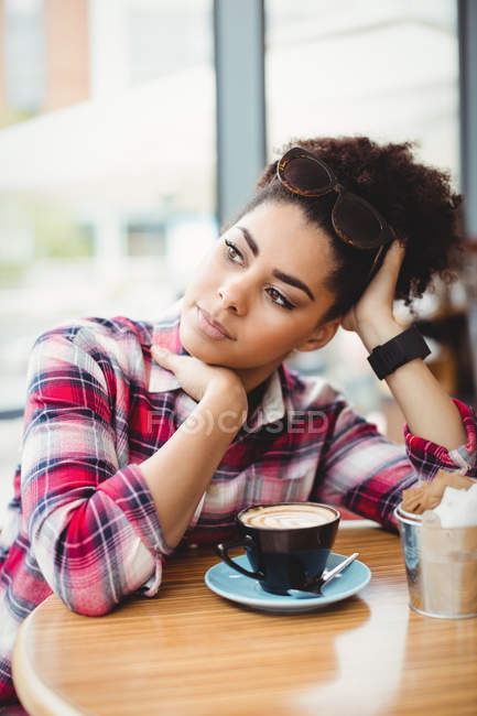 Thoughtful smart woman sitting at table in restaurant — Stock Photo