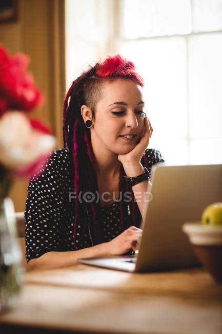 Lächelnde Frau benutzt Laptop während sie zu Hause sitzt — Stockfoto