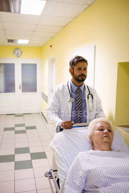 Доктор штовхає пацієнта на ношах в лікарняному коридорі — стокове фото