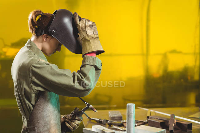 Soldador femenino que sostiene la antorcha de soldadura en el taller - foto de stock