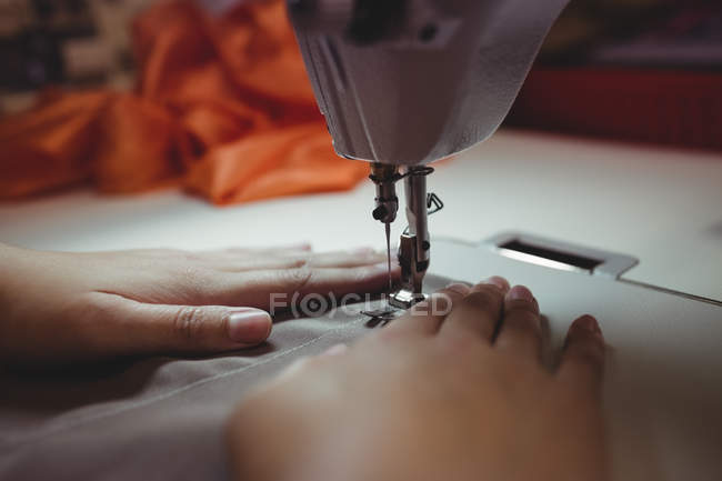 Imagen recortada de costurera femenina en la máquina de coser en el estudio - foto de stock