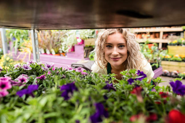Retrato de florista feminina sorridente no centro de jardim — Fotografia de Stock