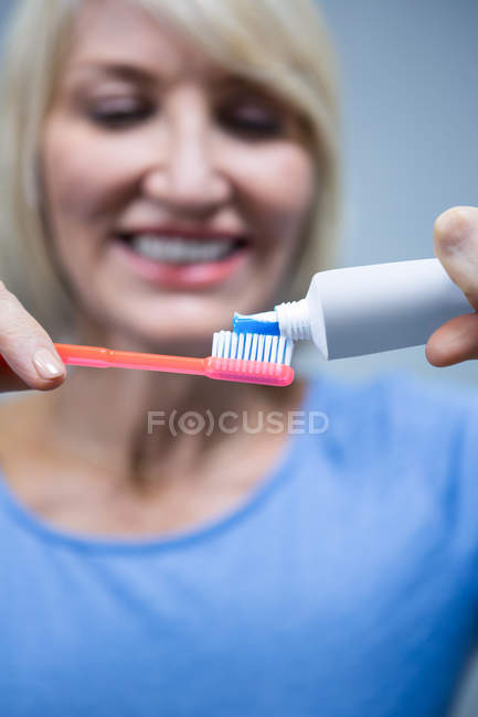 Sorrindo mulher colocando pasta de dentes na escova — Fotografia de Stock