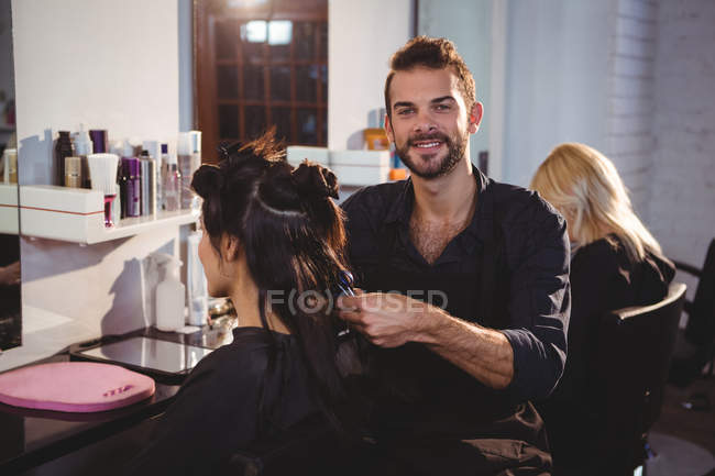 Портрет улыбающегося парикмахера, работающего над клиентом в парикмахерской — стоковое фото