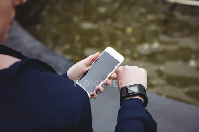 Visão de alto ângulo de empresária segurando telefone celular enquanto verifica o tempo — Fotografia de Stock