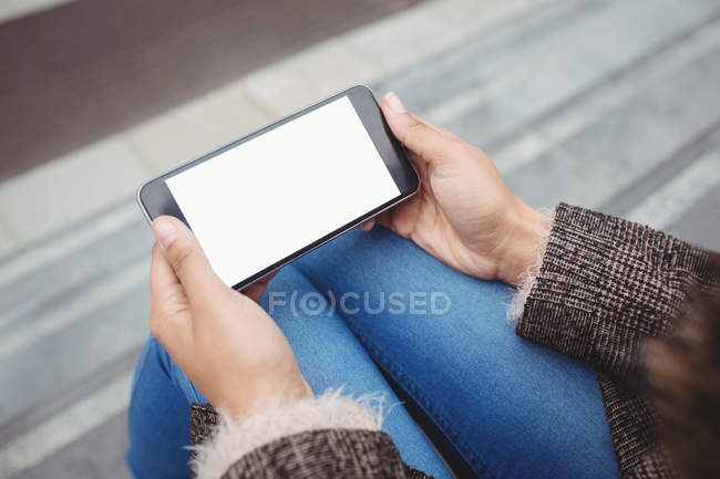 Високий кут зору жінки за допомогою смартфона, сидячи на відкритому повітрі — стокове фото