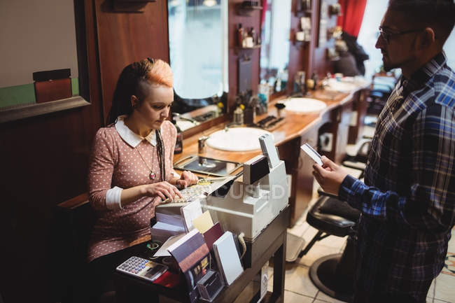 Homem fazendo o pagamento com seu cartão de crédito na barbearia — Fotografia de Stock