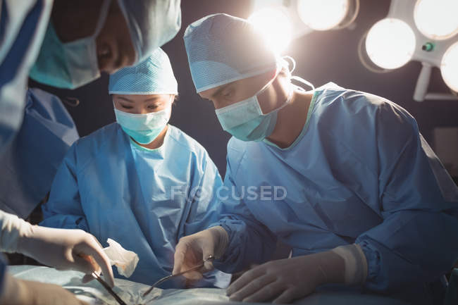 Equipo de cirujanos realizando operación en quirófano en el hospital - foto de stock
