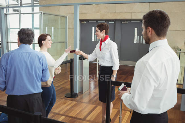 Airline check-in attendant handing boarding pass to passenger at airport check-in counter — Stock Photo