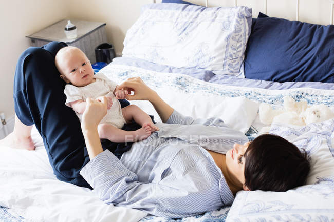 Madre che gioca con il suo bambino in camera da letto a casa — Foto stock