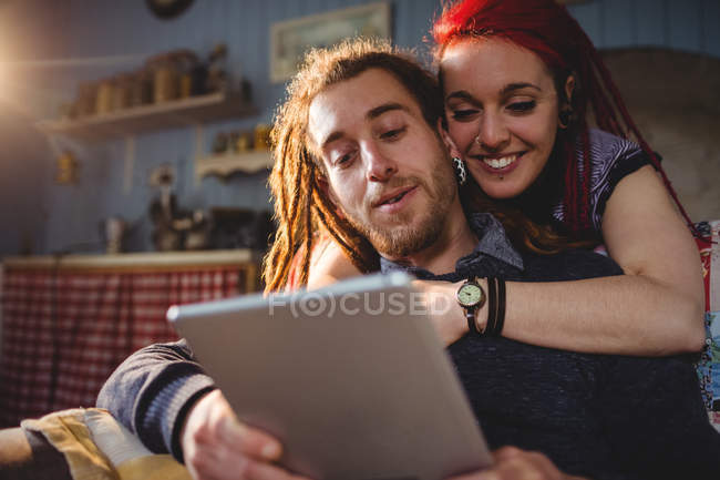 Щаслива пара хіпстерів, використовуючи цифровий планшет, сидячи вдома — стокове фото