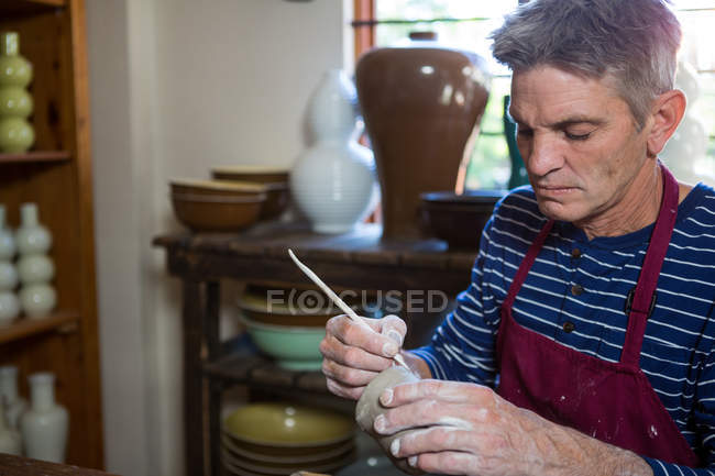 Close-up of male potter carving on pot in pottery workshop — Stock Photo