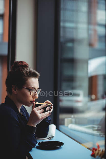 Pensativa mujer de negocios bebiendo café en la cafetería - foto de stock