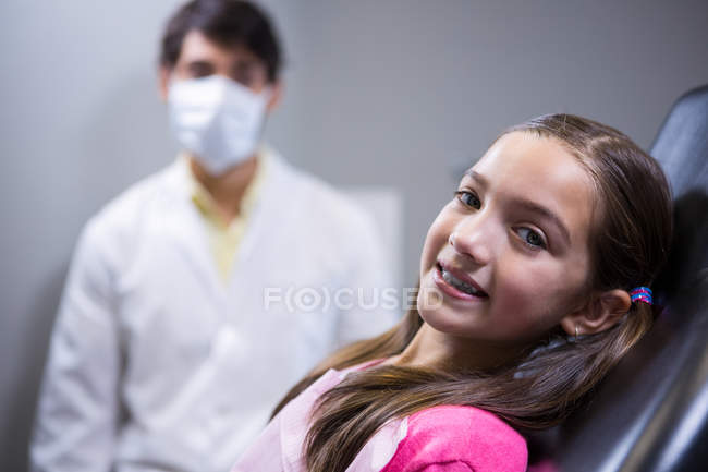 Smiling young patient sitting on dentist chair at clinic — Stock Photo