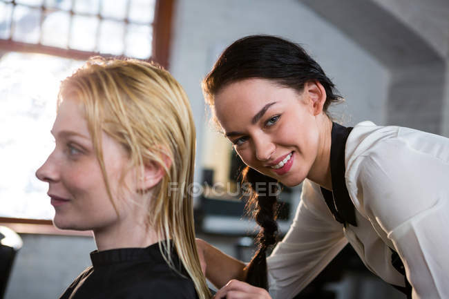 Peluquero peinando el cabello del cliente en el salón - foto de stock