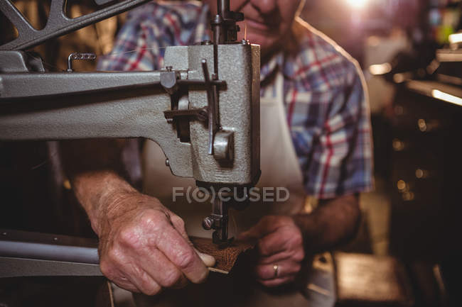Sección media del zapatero usando máquina de coser en taller - foto de stock