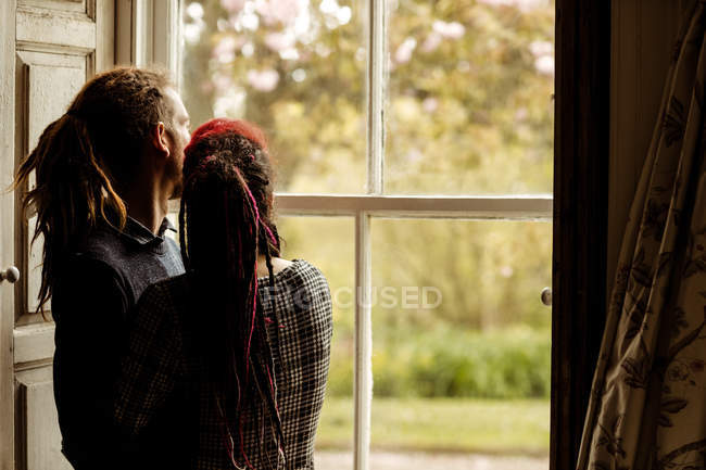 Молода пара захоплюється під час перегляду вікна вдома — стокове фото