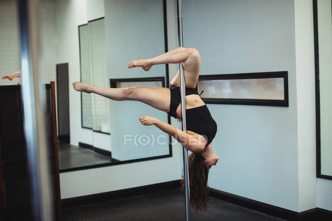 Beautiful Pole dancer practicing pole dance in fitness studio — Stock Photo