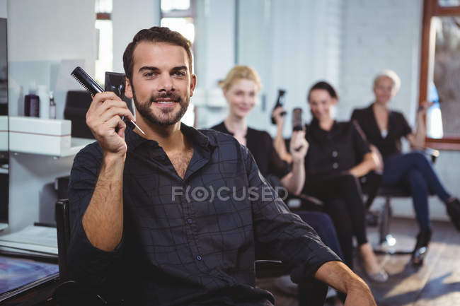 Portrait of smiling hairdressers sitting on chairs in salon — Stock Photo