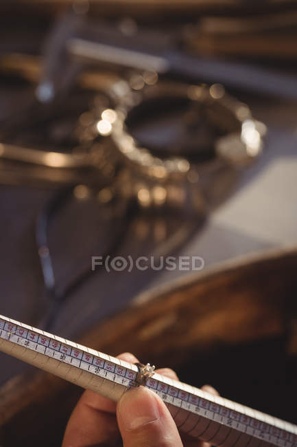 Cropped image of goldsmith measuring ring in workshop — Stock Photo