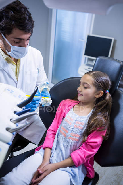 Dentista explicando modelo de boca para paciente jovem na clínica odontológica — Fotografia de Stock