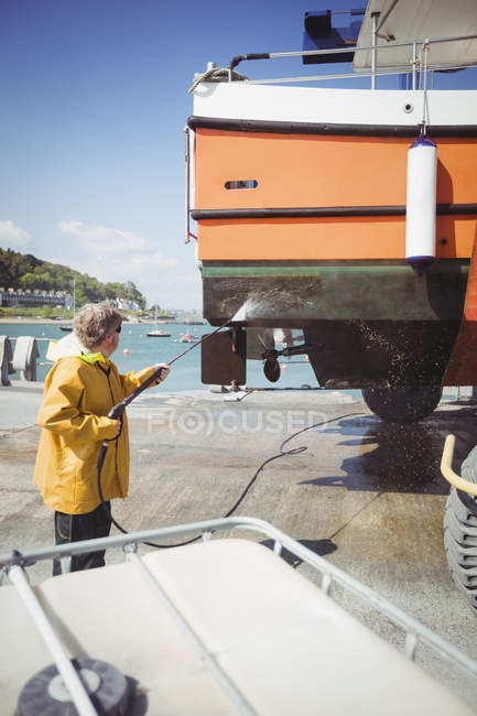 Man cleaning boat with pressure washer on sunny day — Stock Photo