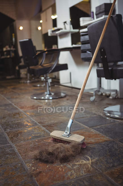 Отходы волос и метла на полу в салоне — стоковое фото
