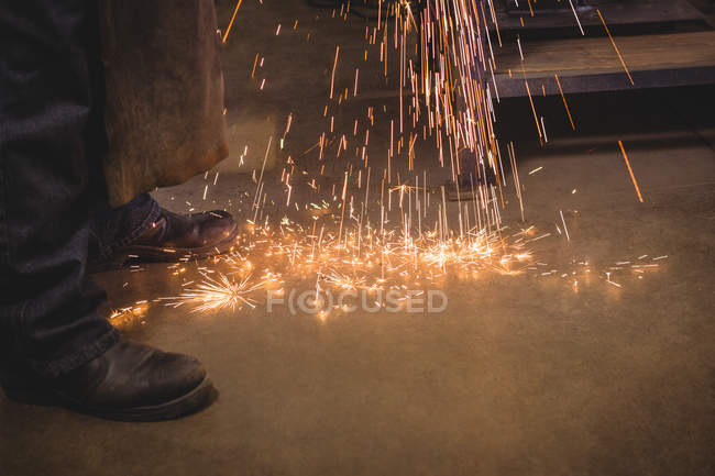 Cropped image of Welder sawing metal in workshop — Stock Photo