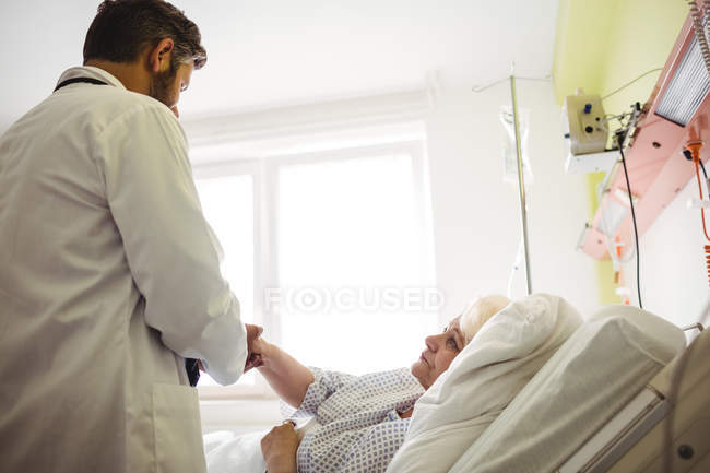 Male doctor examining senior woman in hospital — Stock Photo