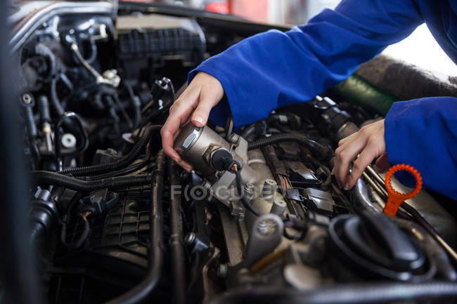 Обрезанное изображение механического обслуживания двигателя автомобиля в ремонтном гараже — стоковое фото