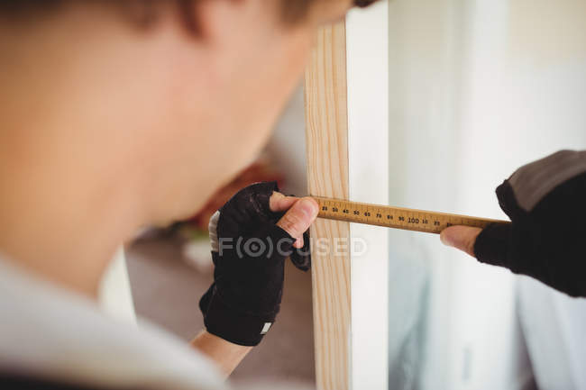 Обрезанное изображение плотника, измеряющего деревянные двери дома — стоковое фото