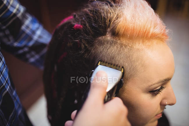 Mulher recebendo seu cabelo aparado com aparador na barbearia — Fotografia de Stock