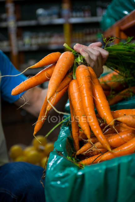 Обрізане зображення Чоловік тримає купу моркви в супермаркеті — стокове фото