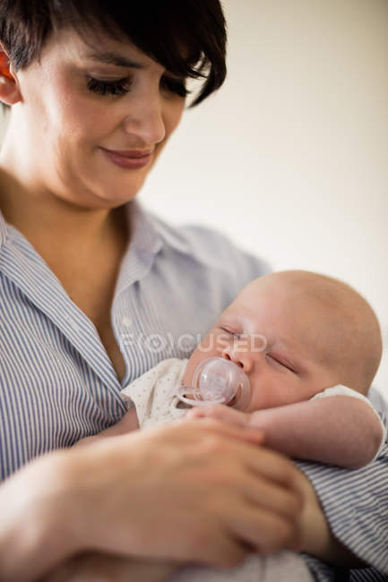 Крупный план малыша с манекеном, спящим дома на руках у матери — стоковое фото