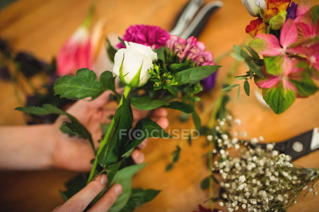 Imagen recortada de florista femenina preparando ramo de flores en su tienda de flores - foto de stock