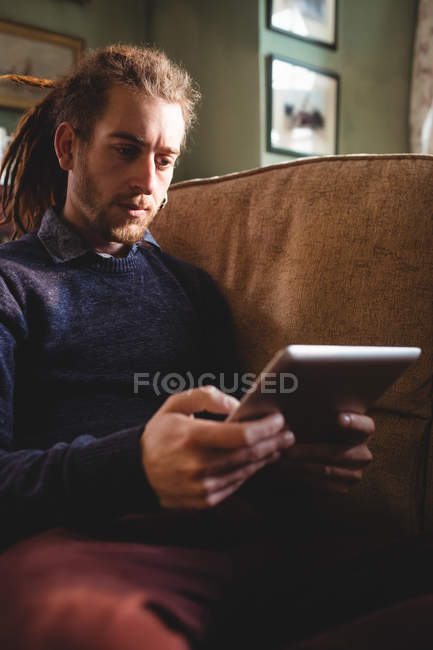 Joven hipster hombre usando tableta digital en el sofá en casa - foto de stock