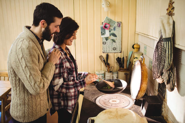 Pareja preparando la comida juntos en la cocina en casa - foto de stock