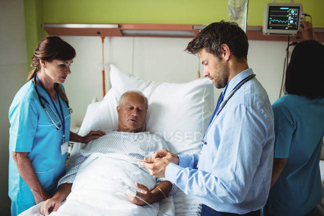 Médico varón mostrando informe a paciente mayor en tableta digital en el hospital - foto de stock