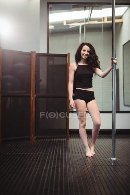 Portrait d'attrayant pole danseur tenant le poteau dans le studio de fitness — Photo de stock